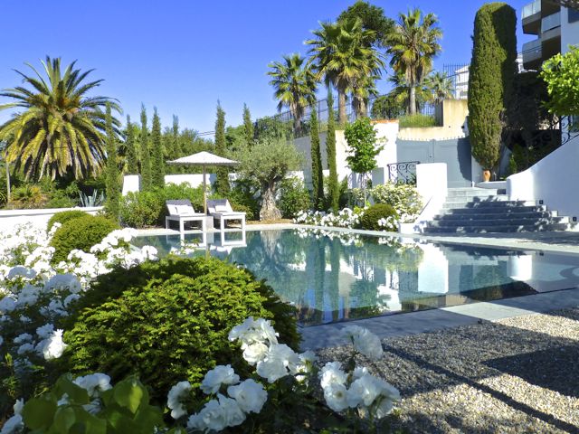 Magical garden and swimming pool, surrounded by white roses and palm trees